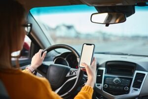 A woman looks at her cellphone while driving. A lawyer can help victims seek damages against negligent motorists in distracted driving crashes, which commonly happen in South Dakota.